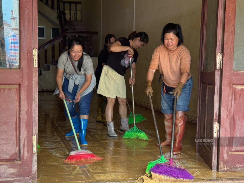 Tại một ngôi nhà vừa rút nước, nhiều người cùng dùng chổi đẩy bùn và nước ra ngoài. Những đôi ủng, chiếc chổi và sự hỗ trợ của hàng xóm trở thành hình ảnh quen thuộc trên khắp các khu dân cư sau lũ.