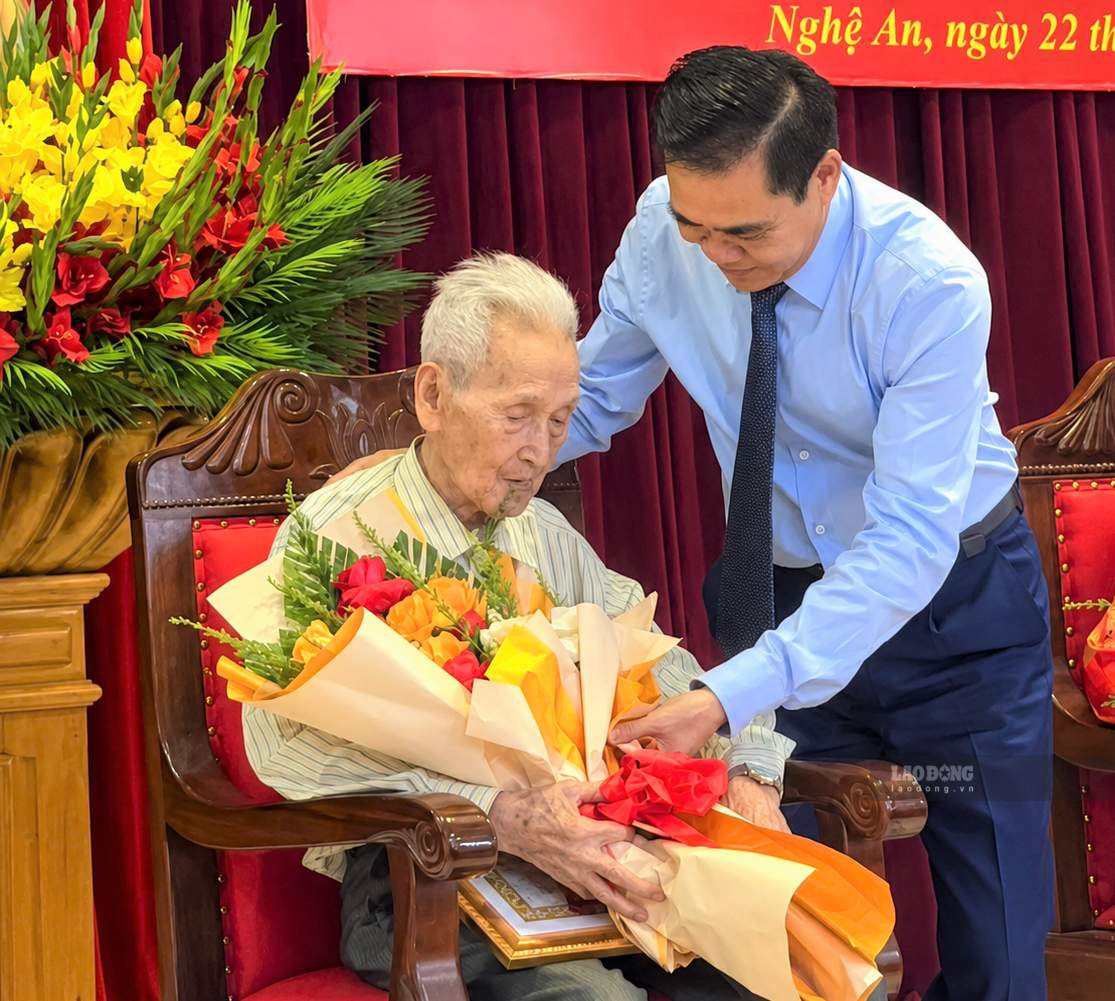 Phó Bí thư Tỉnh ủy, Chủ tịch UBND tỉnh Nghệ An Võ Trọng Hải tặng hoa, trao Huy hiệu 80 năm tuổi Đảng cho cụ Nguyễn Xuân Mão. Ảnh: Duy Chương