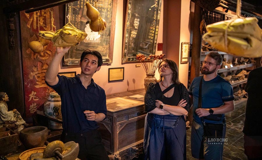 Tour guide Vu Phi Tung introduces to tourists artifacts associated with the medicinal processing profession of ancient Vietnamese people. Photo: Thai Bao