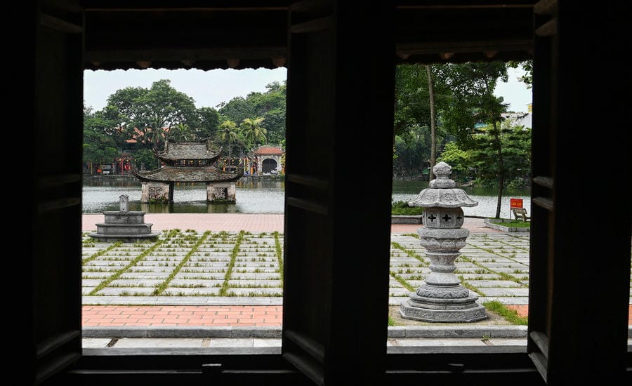 Từ khung cửa gỗ, thủy đình giữa hồ Long Trì hiện ra trong khoảng xanh tĩnh lặng, tạo nên sự giao hòa giữa không gian kiến trúc và thiên nhiên Chùa Thầy.
