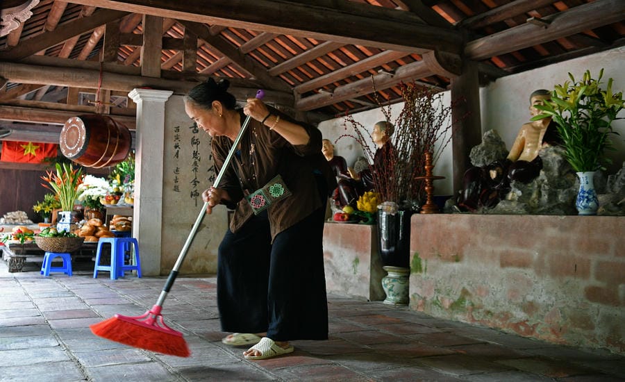 Người phụ nữ lặng lẽ quét rác, một công việc bình dị góp phần gìn giữ sự sạch sẽ và thanh tịnh của không gian chùa.