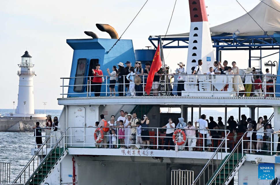 Du khách đi tàu thưởng ngoạn cảnh đẹp dọc đường bờ biển Thanh Đảo. Ảnh: Xinhua