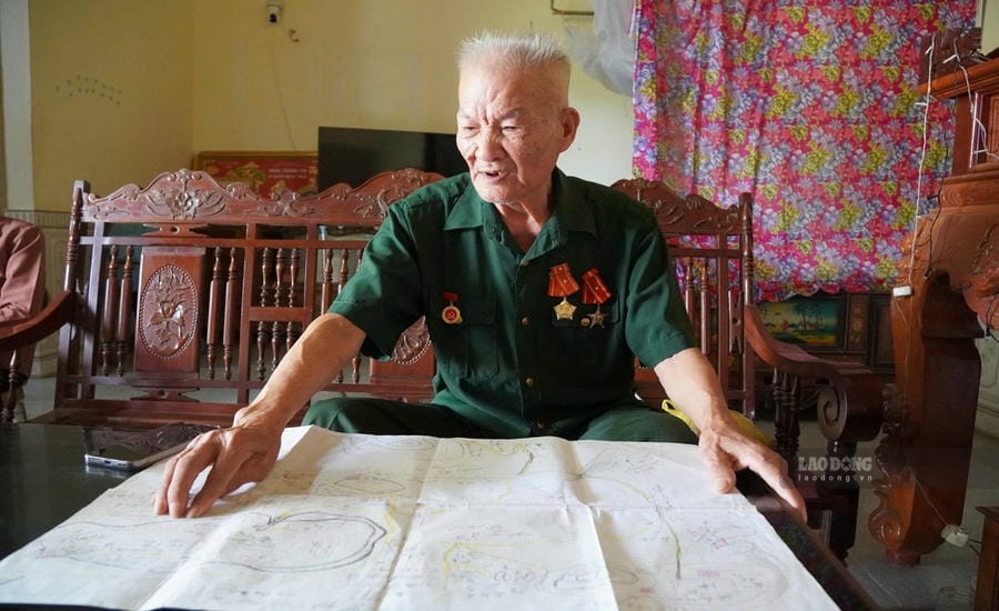 Veteran Nguyen Hong Ha next to a map drawn by himself, helping functional forces find more than 100 martyrs' graves in Laos. Photo: Quach Du