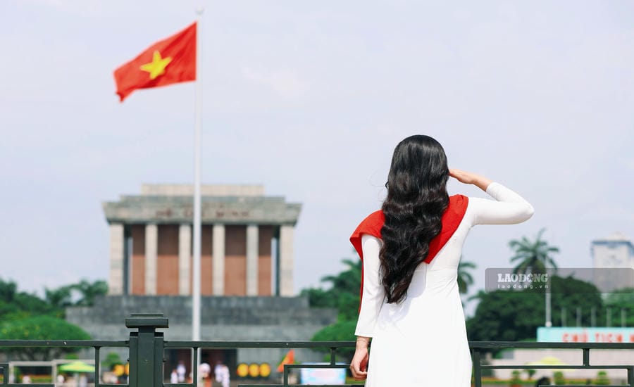 Thiếu nữ dịu dàng trong tà áo dài trắng truyền thống, lưu giữ khoảnh khắc thanh xuân cùng sắc cờ đỏ sao vàng dưới ánh nắng thu chan hòa bên Lăng Bác.  Ảnh: Việt Anh