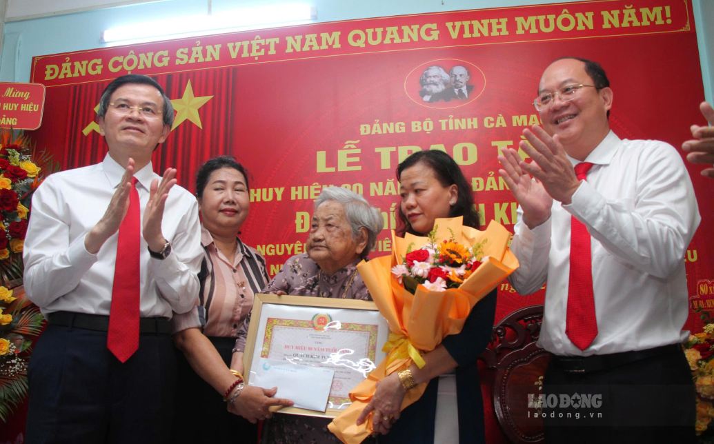 Politburo member Doan Minh Huan and Ca Mau Provincial Party Secretary Nguyen Ho Hai present the 80-year-old badge to Party member Quach Kim Tuyen. Photo: Nhat Ho