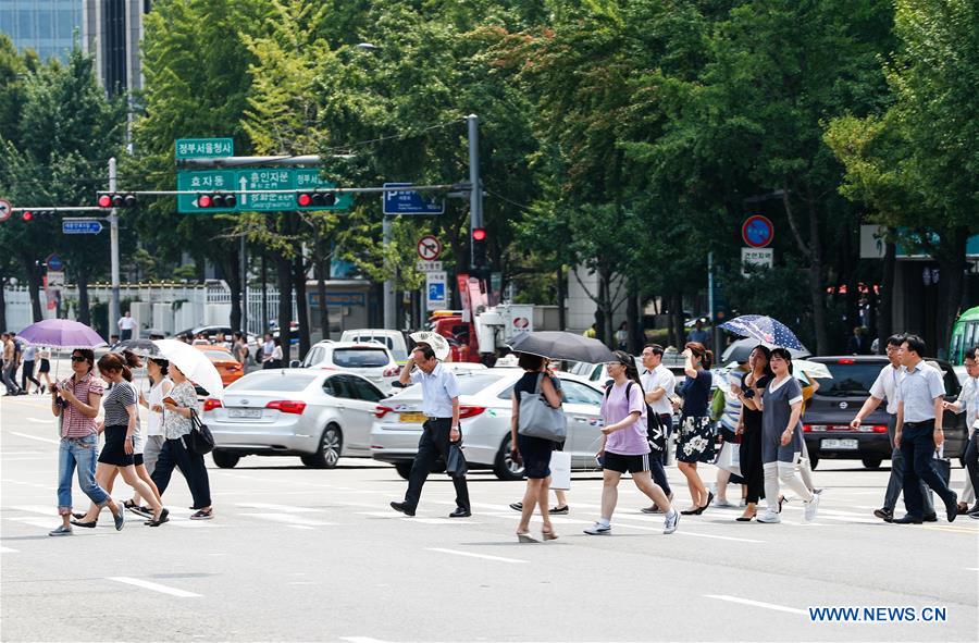 People use umbrellas to avoid the heat on the streets of Seoul, South Korea. Photo: Xinhua