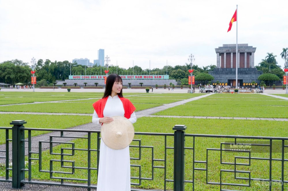 Chị Chi diện áo dài, cầm nón lá đứng trước Lăng Chủ tịch Hồ Chí Minh. Ảnh: Nhân vật cung cấp
