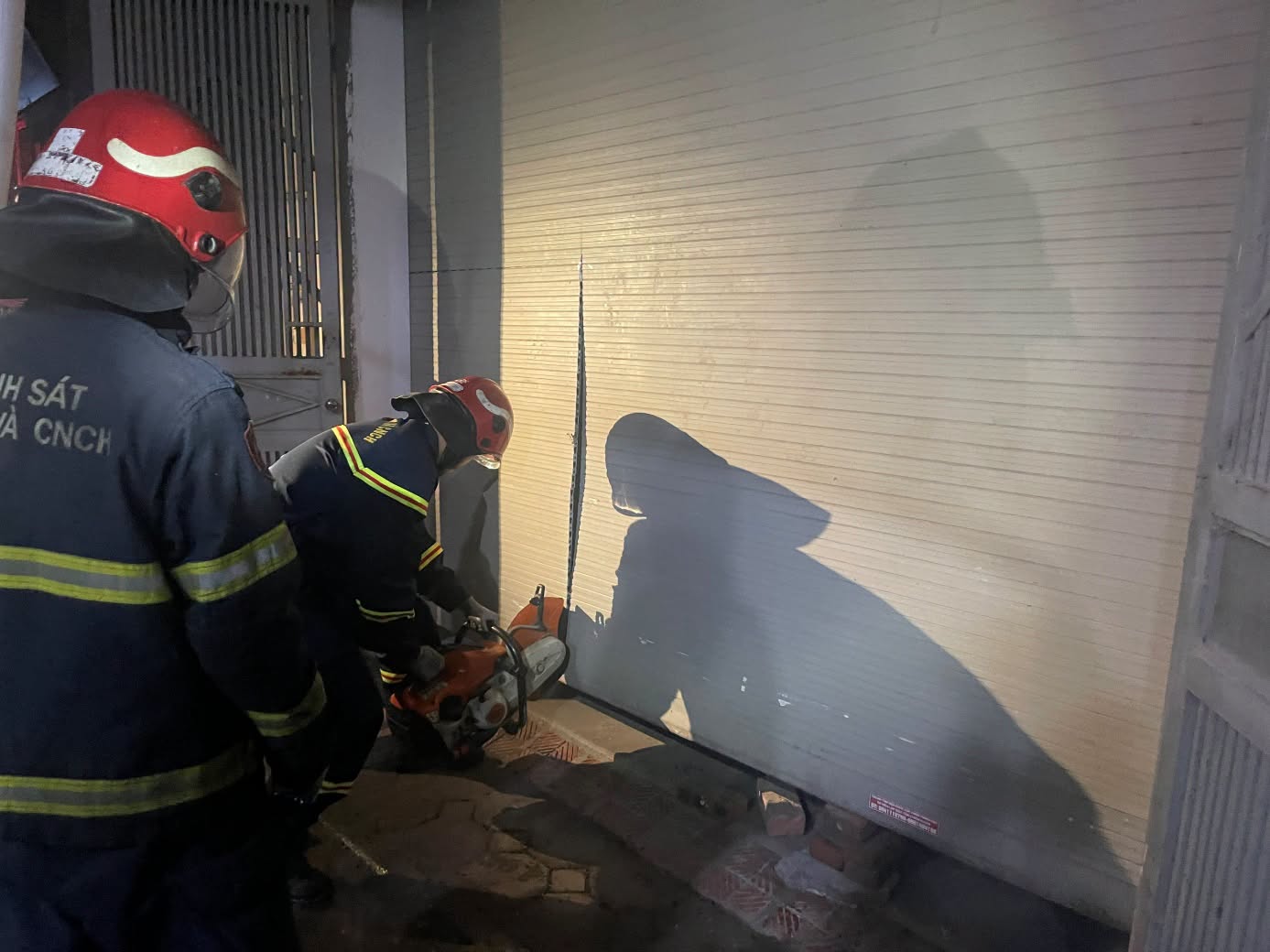 Police break down rolling doors, rescue people trapped in the fire. Photo: Hanoi City Police