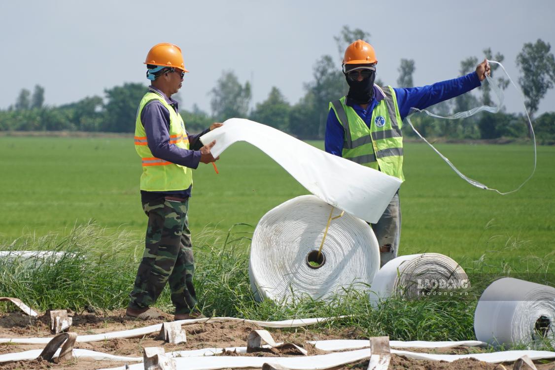 Ông Nguyễn Văn Út Nhỏ (bên trái) làm công việc kẻ bấc thấm ngang, may vải để trải cát lên. Ảnh: Tạ Quang
