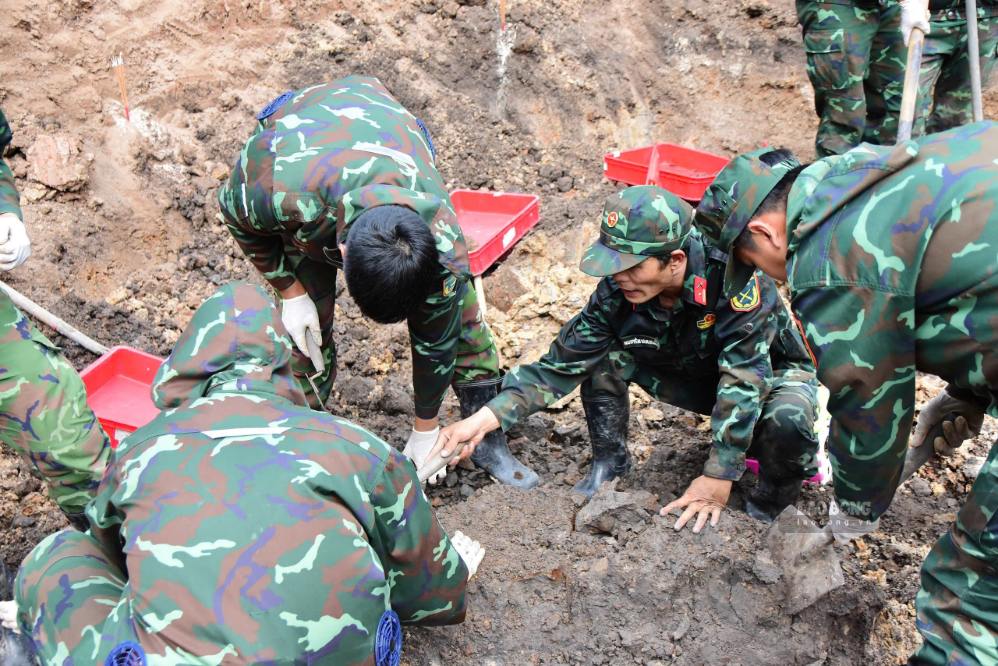 Lực lượng làm nhiệm vụ thận trọng bóc tách từng lớp đất nhằm tìm kiếm hài cốt và di vật của các liệt sĩ.