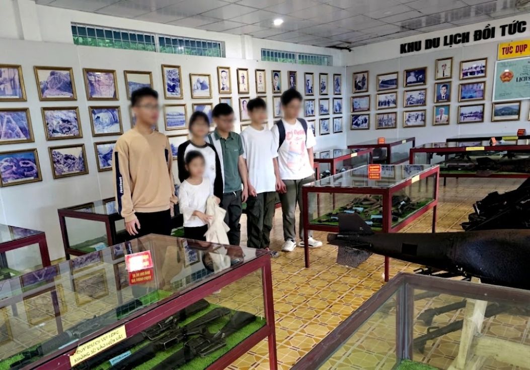 Du khách trẻ háo hức chụp ảnh lưu niệm tại nhà trưng bày hiện vật chiến tranh tại di tích Đồi Tức Dụp. Ảnh: Công ty Cổ phần Du lịch An Giang cung cấp
