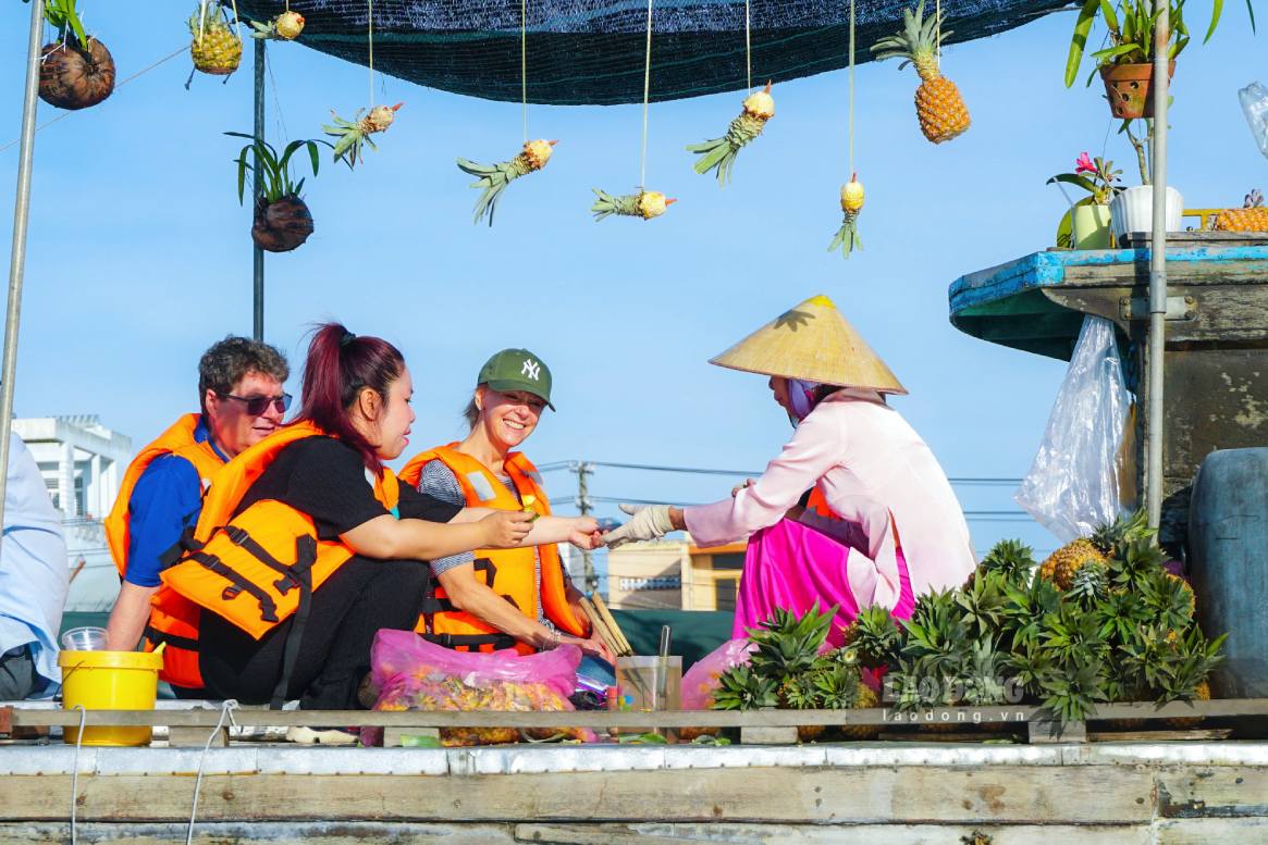Cảnh thương hồ buôn bán trên sông Cần Thơ và du khách nước ngoài trải nghiệm ăn khóm trên ghe. Ảnh: Tạ Quang
