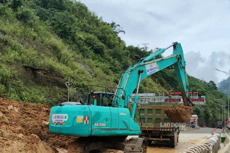 Máy móc được huy động hót dọn đất đá, xử lý điểm sạt lở tại khu vực trạm thu phí BOT trên đường tỉnh 155. Ảnh: Đinh Đại