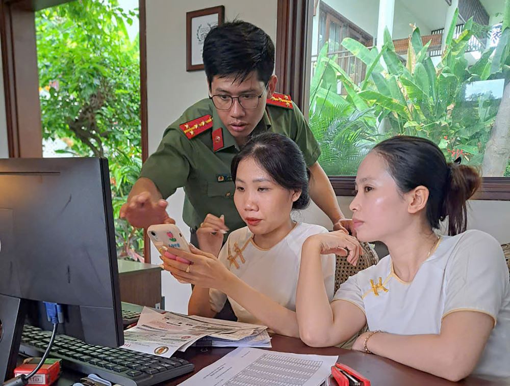 Cán bộ Phòng Quản lý Xuất nhập cảnh hướng dẫn nhân viên cơ sở lưu trú thực hiện khai báo tạm trú trên thiết bị di động. Ảnh: Công an cung cấp