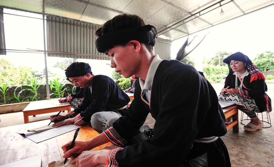 Người Dao Tiền thuộc tổ dân phố Tà Loọng, phường Thảo Nguyên, tỉnh Sơn La học viết chữ và điệu múa truyền thống. Ảnh: Bỉnh Khiêm