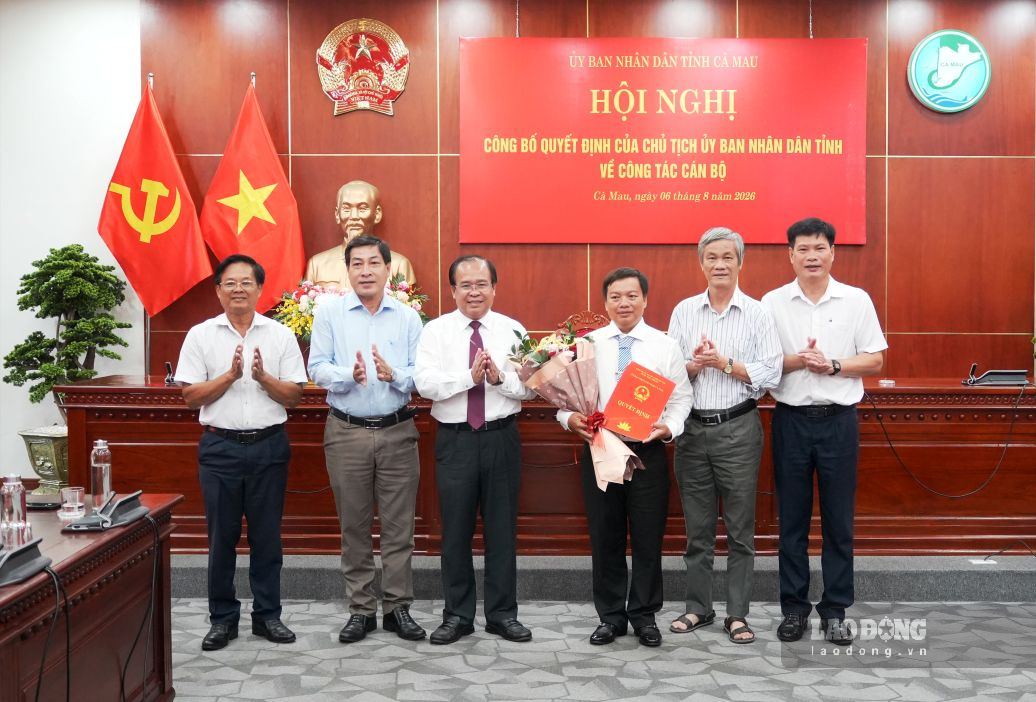 Phó Chủ tịch UBND tỉnh Cà Mau Nguyễn Minh Luân trao quyết định, tặng hoa đồng chí Huỳnh Ngọc Linh và chụp ảnh lưu niệm cùng Ban Giám đốc Sở Y tế. Ảnh: Nhật Hồ.