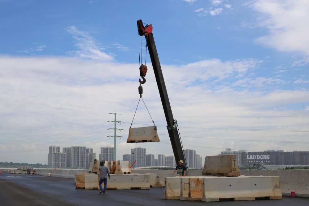 Công nhân hoàn thiện dải phân cách cứng trên đoạn Vành đai 3 đã được thảm mặt đường.