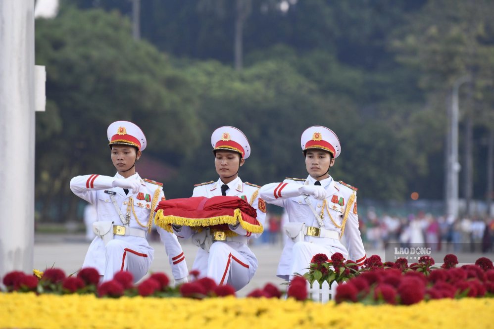 Ba chiến sĩ mang khay đựng Quốc kỳ tách khỏi đội hình, tiến về phía cột cờ để chuẩn bị thực hiện nghi thức.