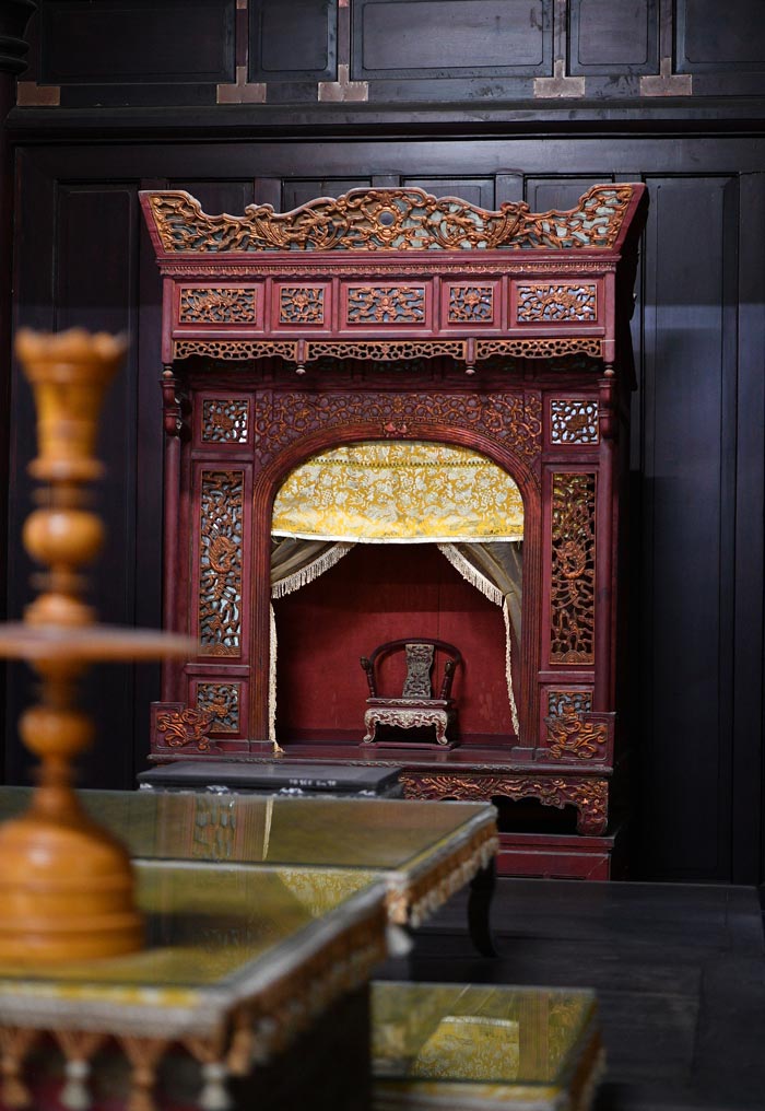 Một khám thờ bằng gỗ chạm khắc tinh xảo trong không gian nội thất Lăng Tự Đức, nổi bật với kỹ thuật sơn son thếp vàng cùng các họa tiết rồng, mây. Ánh sáng và những lớp rèm tạo chiều sâu, làm nổi bật vẻ trang nghiêm, cầu kỳ của nội thất cung đình.