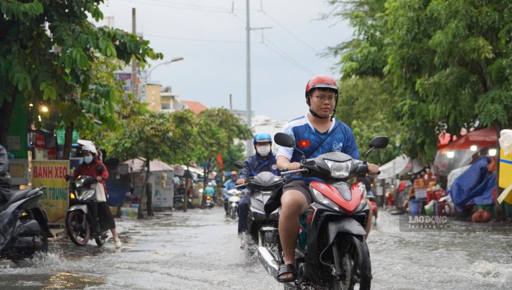 Các phương tiện di chuyển chậm qua đoạn đường ngập do triều cường.