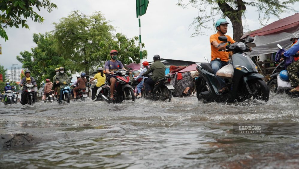 Nước ngập mặt đường khiến việc đi lại của người dân gặp nhiều khó khăn.