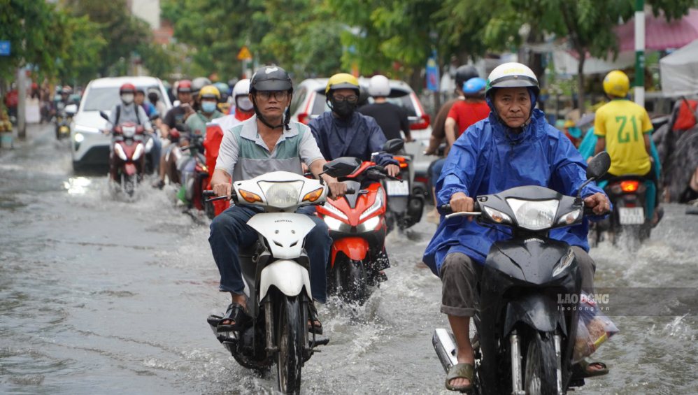 Xe máy chật vật đi qua khu vực ngập, nhiều người phải giảm tốc độ.