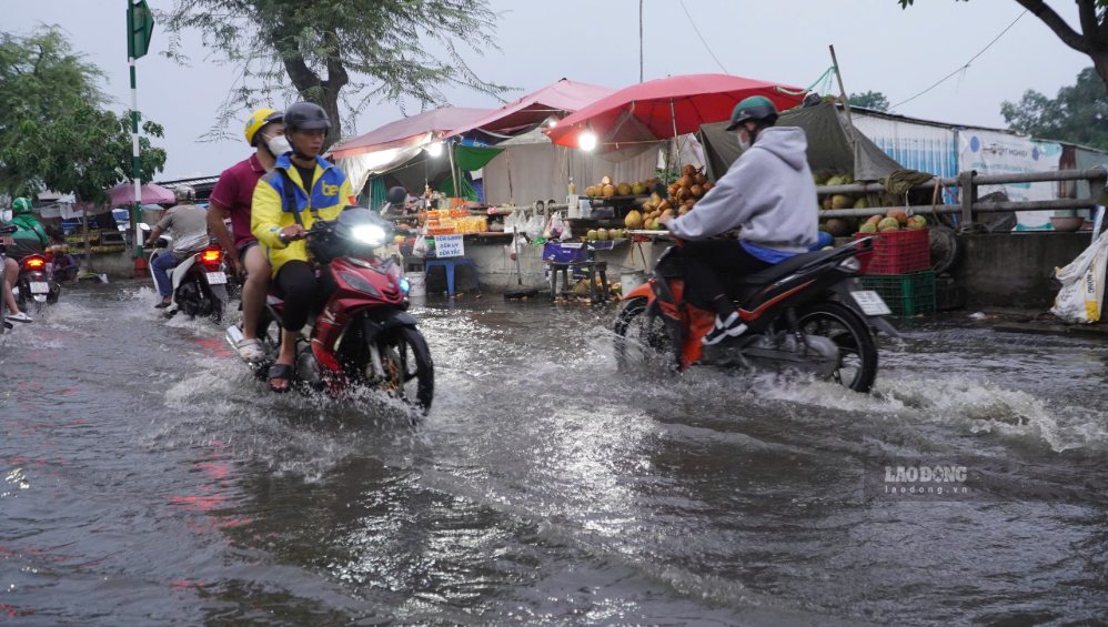 Các phương tiện nối đuôi nhau di chuyển chậm qua đoạn đường ngập.