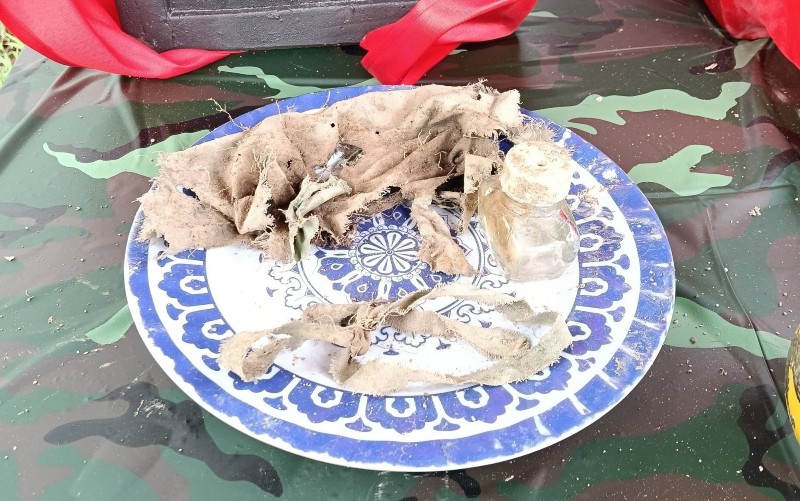 Lực lượng chức năng tìm thấy 2 lọ thủy tinh, một số cúc áo, mảnh khăn và vải băng bó vết thương. Trong đó, có 1 hài cốt đủ điều kiện lấy mẫu phục vụ giám định ADN. Ảnh: BCH Quân sự Quế Phước 