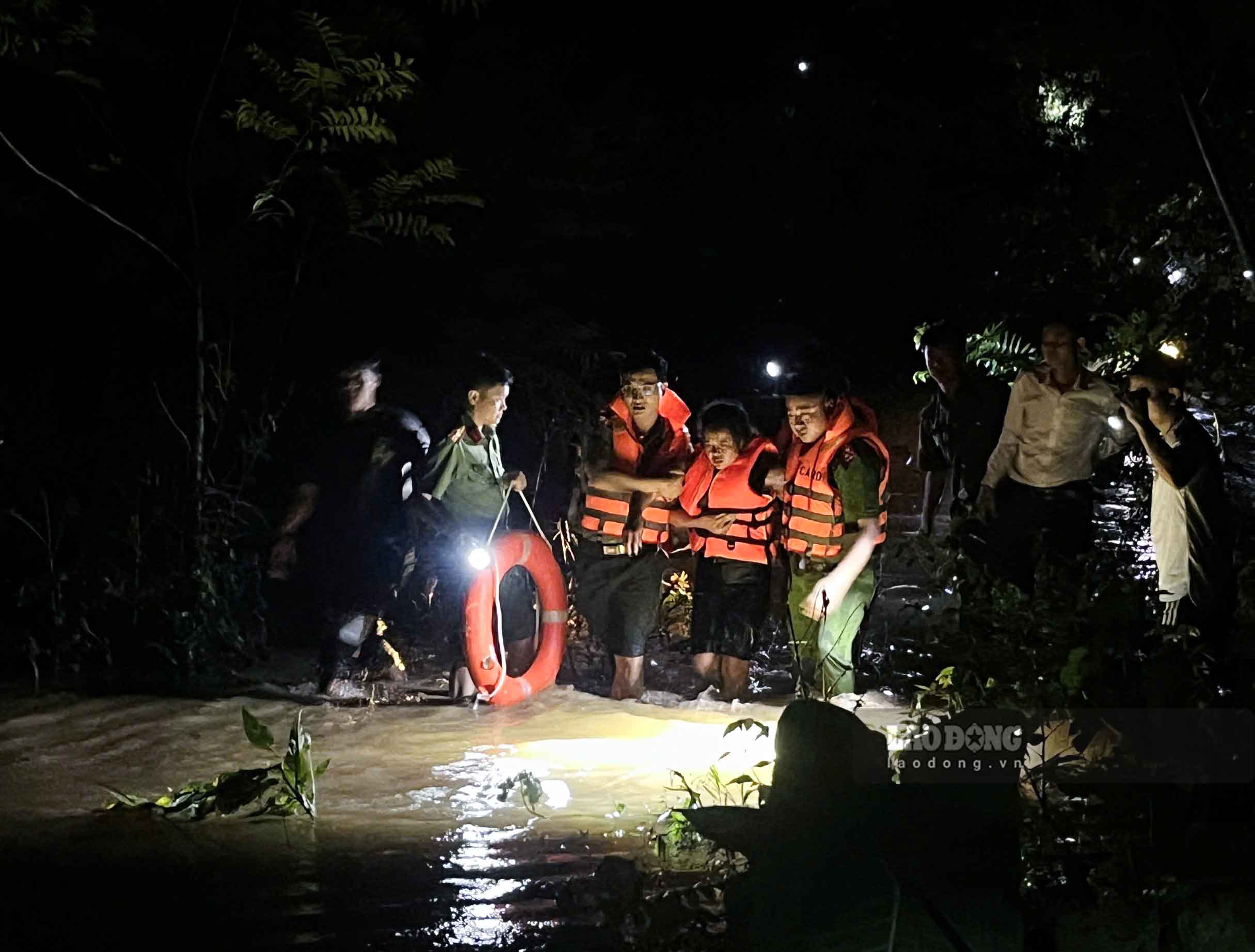 Police and soldiers supported to take the woman across the deep flooded bridge for emergency treatment. Photo: Tam Pham