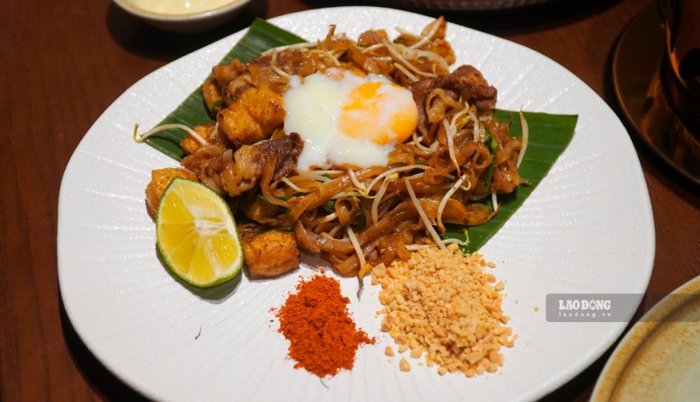 Pad Thai được xào cùng tôm, trứng, giá và rau hẹ, dùng kèm đậu phộng, ớt và chanh.