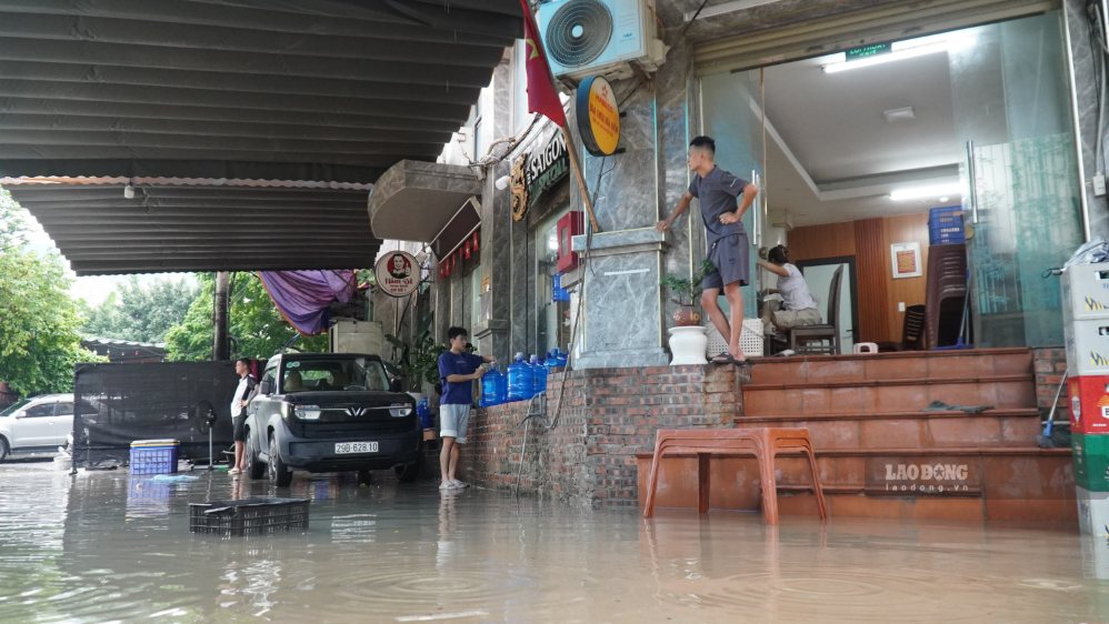 Nước ngập trước cửa khiến hoạt động kinh doanh của các cửa hàng bị gián đoạn. Ảnh: Minh Vũ