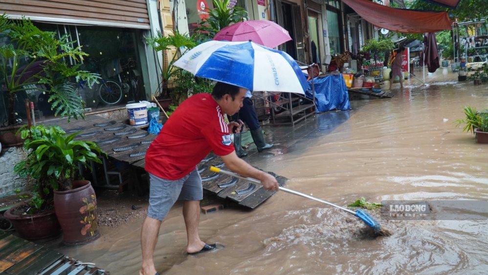 Anh Quyên tranh thủ quét dọn bùn đất khi nước rút bắt đầu rút. Ảnh: MInh Vũ