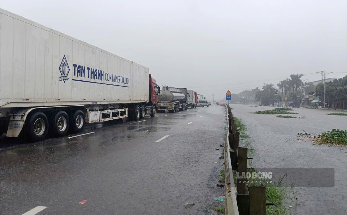 Các xe tải cỡ lớn di chuyển chậm qua điểm ngập. Ảnh: Quách Du (chụp ngày 17.9.2026)