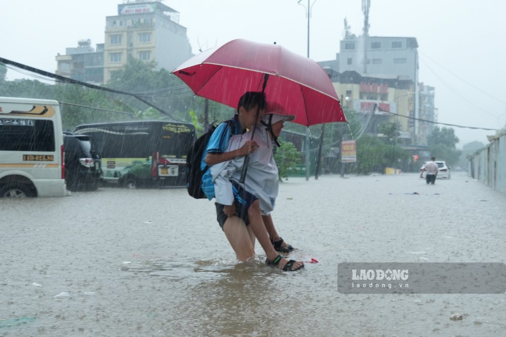 Parents carry students through flooded spots on Dong Me street (Tu Liem ward, Hanoi), morning of September 17. Photo: Song Huu