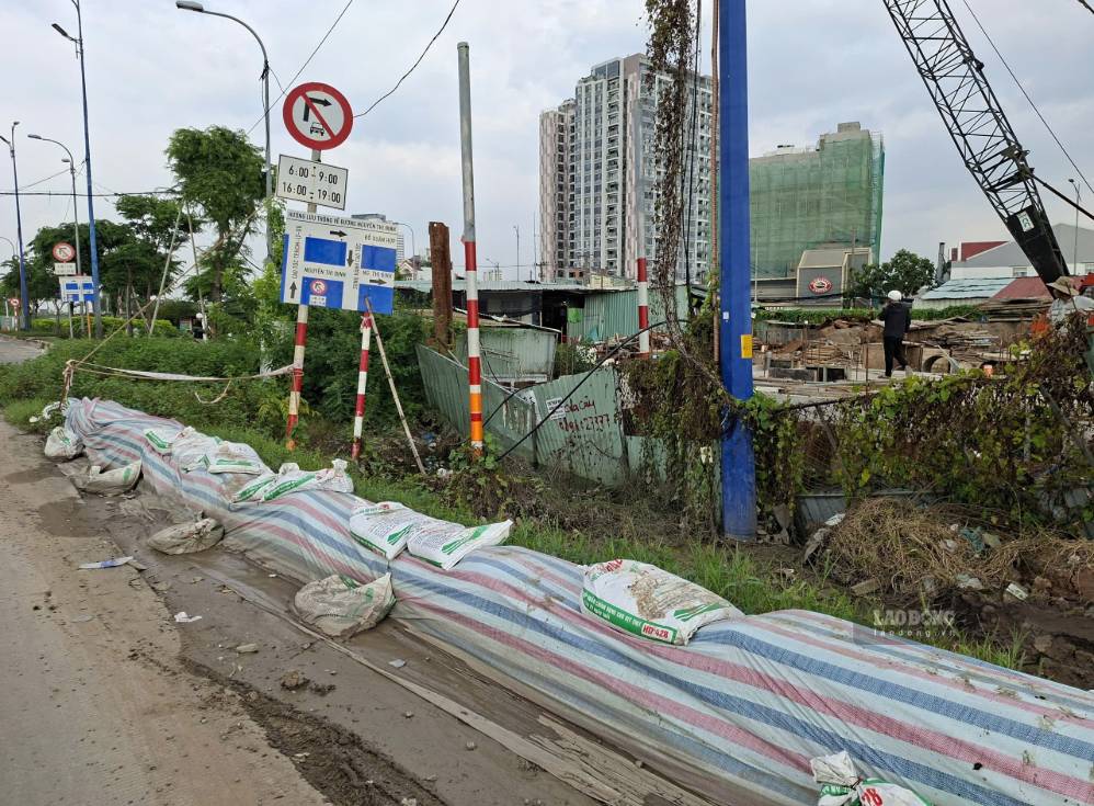 Đắp bờ bao quanh trạm bơm nút giao An Phú để ngăn nước tràn vào. Ảnh: Minh Quân