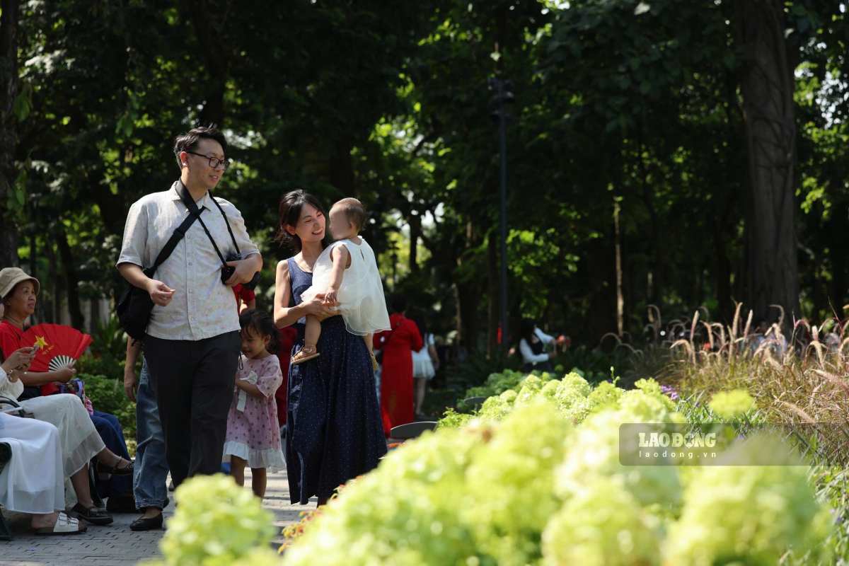 Du khách chụp ảnh bên vườn hoa tại hồ Gươm. Ảnh: Hải Nguyễn