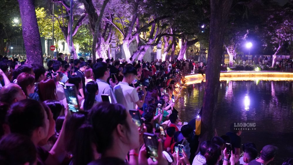 Nhiều gia đình và bạn trẻ ghi lại khoảnh khắc pháo hoa rực rỡ giữa trung tâm Hà Nội. Ảnh: Minh Vũ