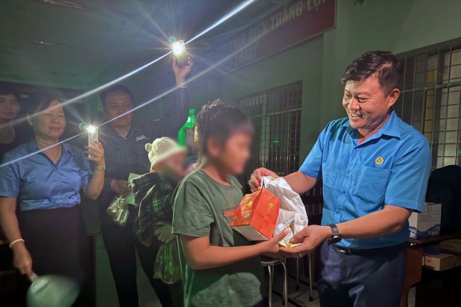 Chairman of the Trade Union of Industrial Parks and Economic Zones of Dong Thap Nguyen Thanh Nhan presents Mid-Autumn gifts to union members' children under the phone light of trade union officials. Photo: Thanh Nhan