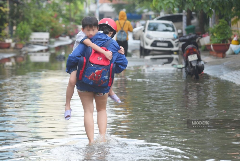 Parents take their children home from school through flooded roads in Ho Chi Minh City. Photo: Chan Phuc