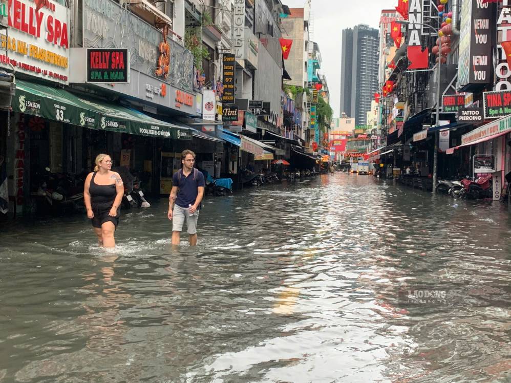 Tourists wading through water moving on Bui Vien street on September 23. Photo: Thai Bao
