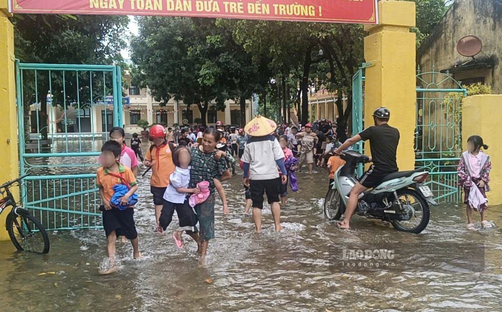 Phụ huynh, học sinh bì bõm lội nước tại Trường Tiểu học Tống Sơn - phân hiệu 1. Ảnh: Quách Du (ảnh chụp ngày 24.9.2026)