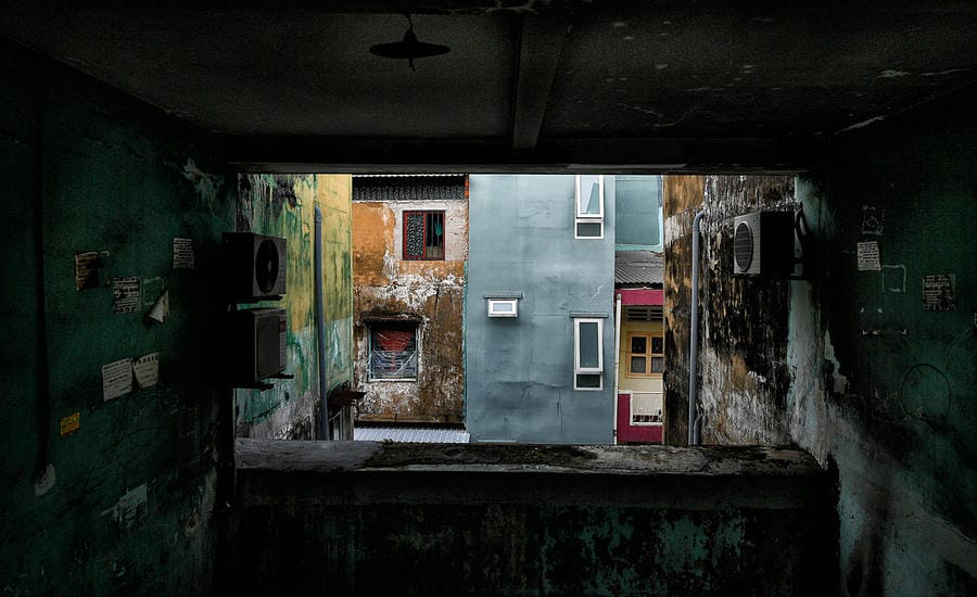 Through the window of an old apartment building, peeling walls, faded paint and renovated buildings over many generations create layers of memories overlapping.