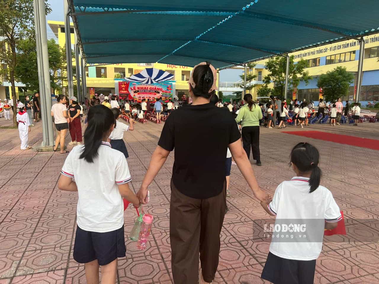 Ms. Chien - a worker in Thang Long Industrial Park brought her 2 daughters to school to attend the new school year opening ceremony. Photo: Minh Huong.