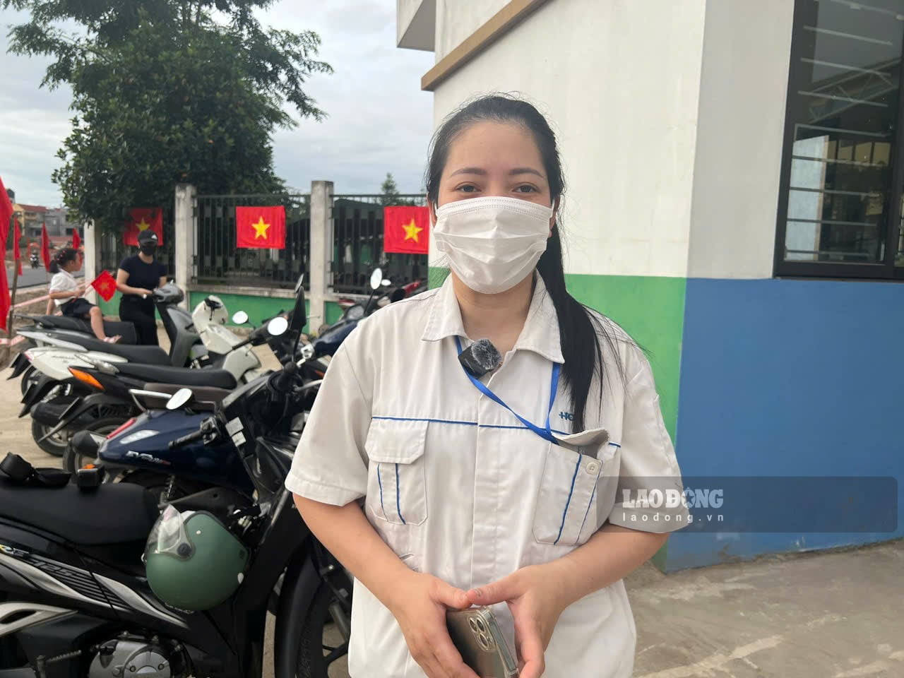 Chị Vũ Thị Hồng tranh thủ trước giờ vào ca để đưa con đang học lớp 3 đến dự lễ khai giảng. Ảnh: Minh Hương.