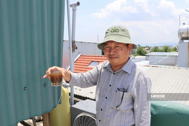 A resident (Cam Thanh ward, Quang Ngai province) and a glass of water taken from the domestic water system at home before being led into the filtration system. Photo: Vien Nguyen