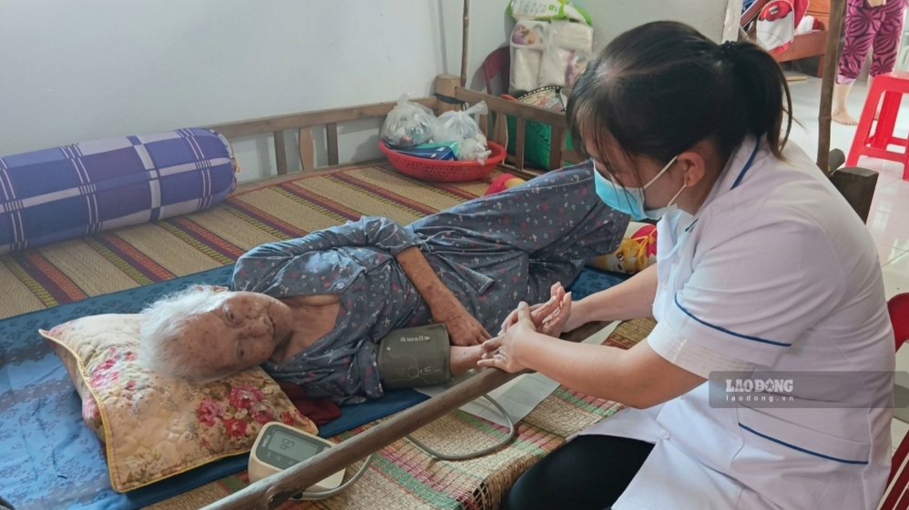 Nhân viên y tế kiểm tra huyết áp cho cụ già ngay tại giường. Ảnh: Hoàng Lộc
