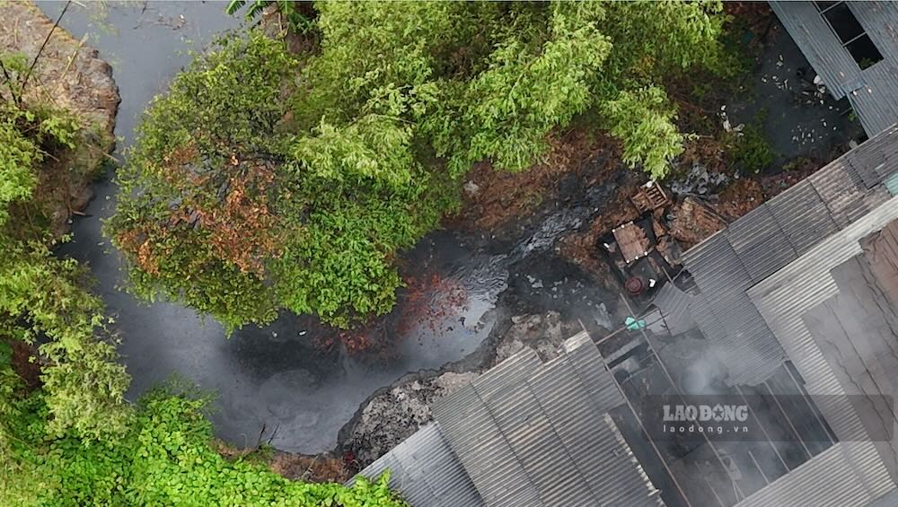 Dòng nước đen kịt chảy vào, lấp đầy hố đào phía sau khu vực nhà máy giấy. Ảnh: Phóng viên