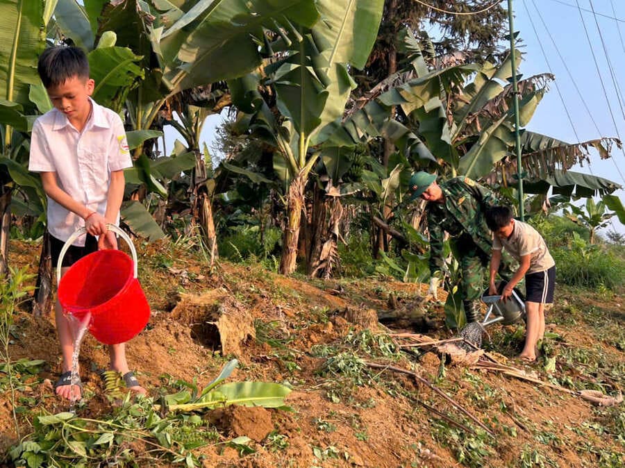 Bộ đội Biên phòng hướng dẫn con nuôi biên phòng chăm sóc cây quýt. Ảnh: Bộ đội biên phòng Lào Cai cung cấp