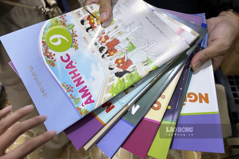 Trên tay anh V. là những quyển sách giáo khoa lớp 9 mua được cho em vào tối ngày 6.9. Ảnh: Phong Linh.