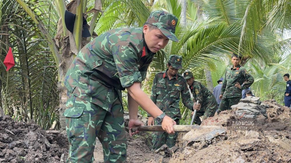 Lực lượng chức năng tìm kiếm hài cốt liệt sĩ tại nghĩa trang tạm ở xã Đồng Khởi. Ảnh: Hoàng Lộc